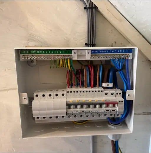 Open consumer unit neatly wired with colour-coded cables, RCBOs and surge protection