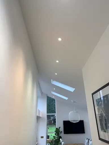 Recessed LED downlights and skylights fitted into the vaulted ceiling of a bright modern room