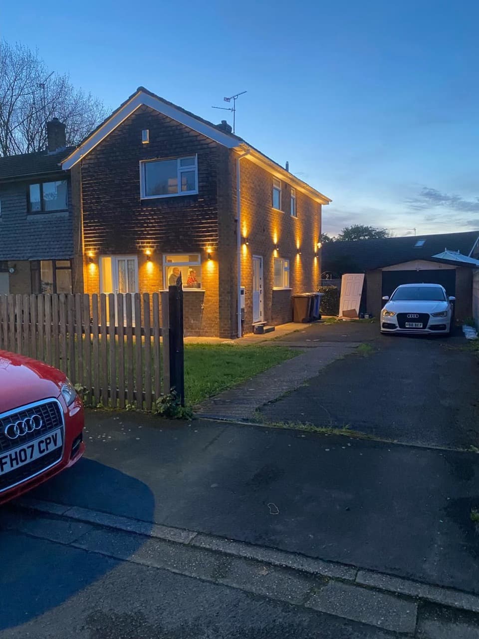 Detached house lit at dusk with warm wall downlights washing the brickwork