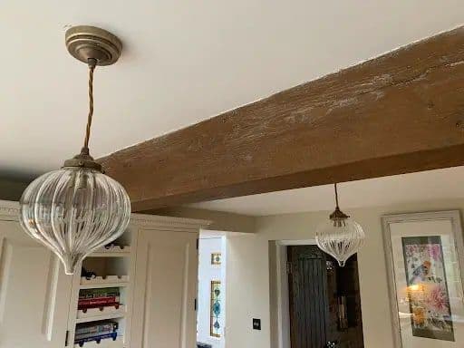 Decorative glass pendant lights fitted beneath an oak beam in a period cottage
